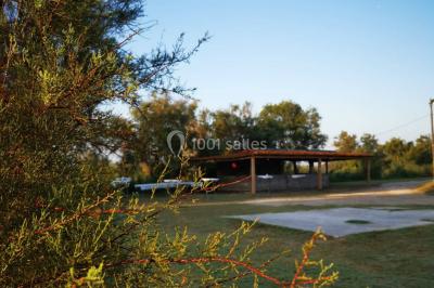Maison blanche aux volets bleus éclairée la nuit, entourée d'arbres et d'une pelouse.