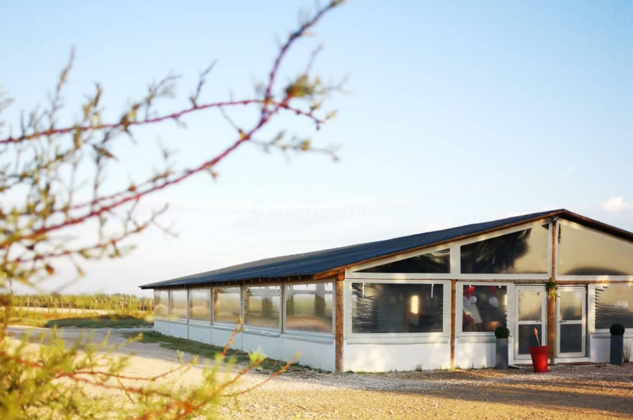 Bâtiment rectangulaire avec des parois transparentes, situé dans un environnement rural sous un ciel dégagé.