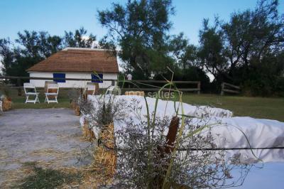 Maison blanche aux volets bleus éclairée la nuit, entourée d'arbres et d'une pelouse.
