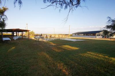 Maison blanche aux volets bleus éclairée la nuit, entourée d'arbres et d'une pelouse.