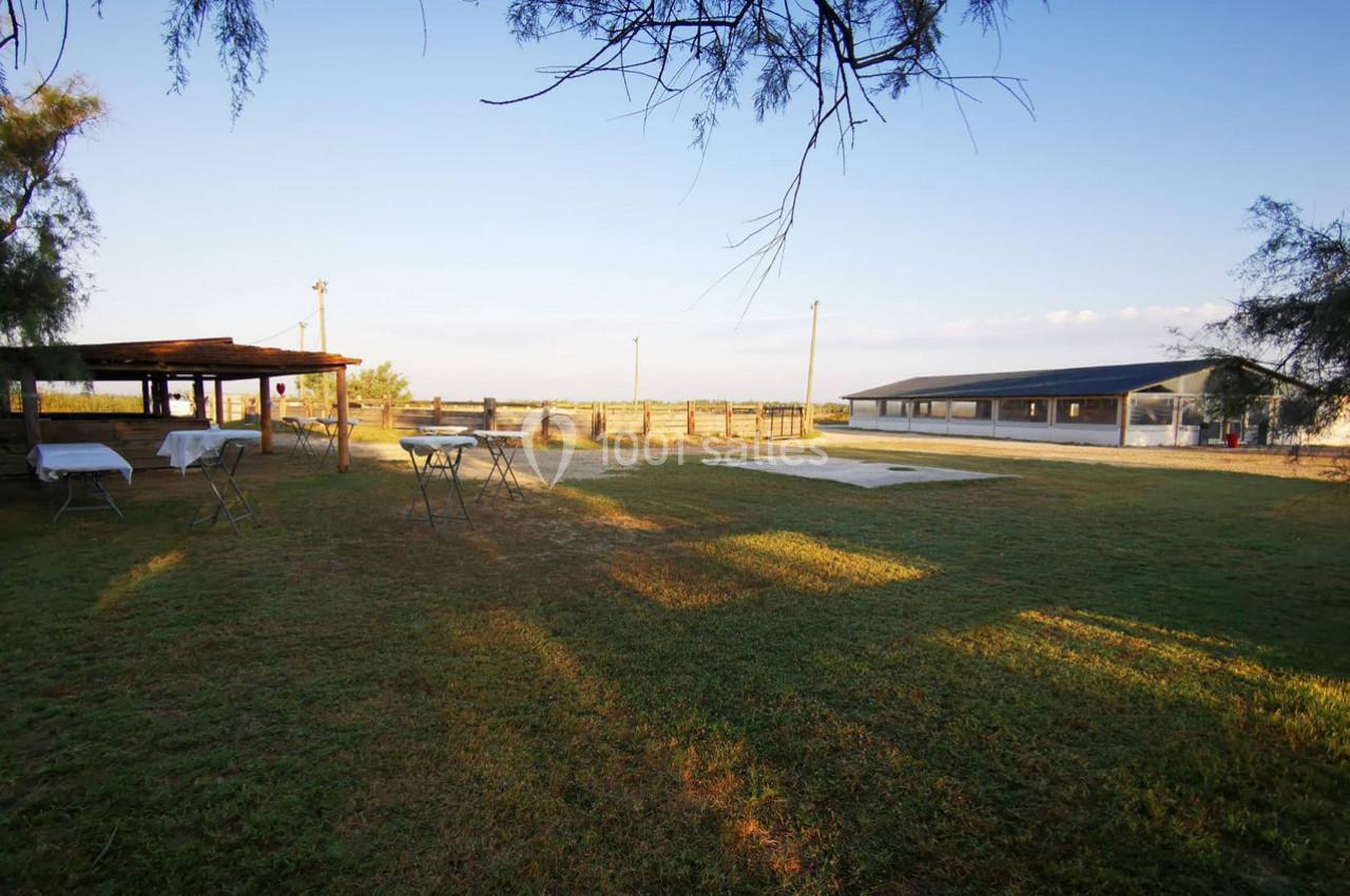Espace extérieur avec pelouse, tables et structures en bois sous un ciel dégagé en fin de journée.