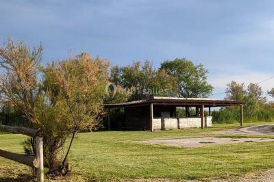 Maison blanche aux volets bleus éclairée la nuit, entourée d'arbres et d'une pelouse.