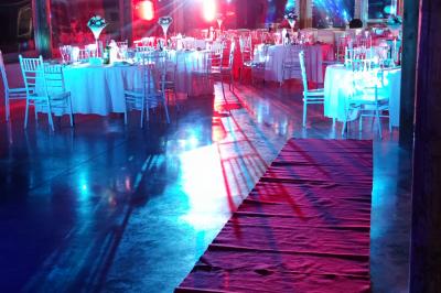 Maison blanche aux volets bleus éclairée la nuit, entourée d'arbres et d'une pelouse.