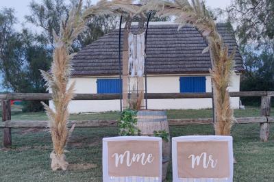 Maison blanche aux volets bleus éclairée la nuit, entourée d'arbres et d'une pelouse.