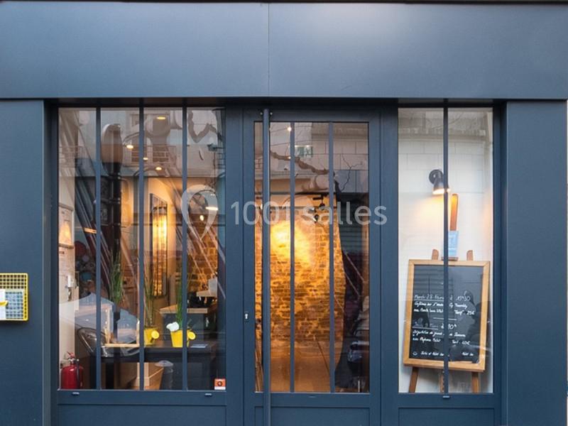 Façade d'un restaurant avec une porte vitrée, un tableau noir affichant le menu et un intérieur éclairé visible.