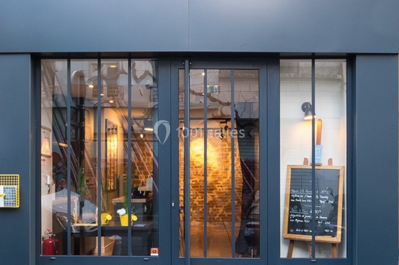 Façade d'un restaurant avec une porte vitrée, un tableau noir affichant le menu et un intérieur éclairé visible.
