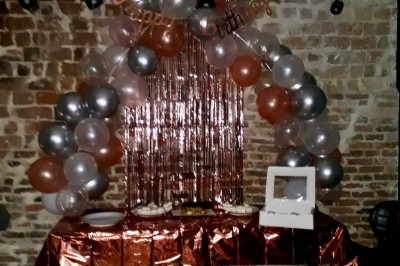 Salle de réunion moderne avec table noire, chaises, écran de projection, paperboard et cuisine ouverte en arrière-plan.