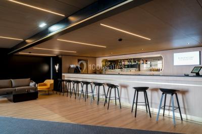 Terrasse extérieure avec mobilier de jardin, vue sur des bâtiments modernes et ciel dégagé en arrière-plan.