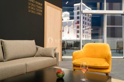 Terrasse extérieure avec mobilier de jardin, vue sur des bâtiments modernes et ciel dégagé en arrière-plan.