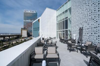 Terrasse extérieure avec mobilier de jardin, vue sur des bâtiments modernes et ciel dégagé en arrière-plan.