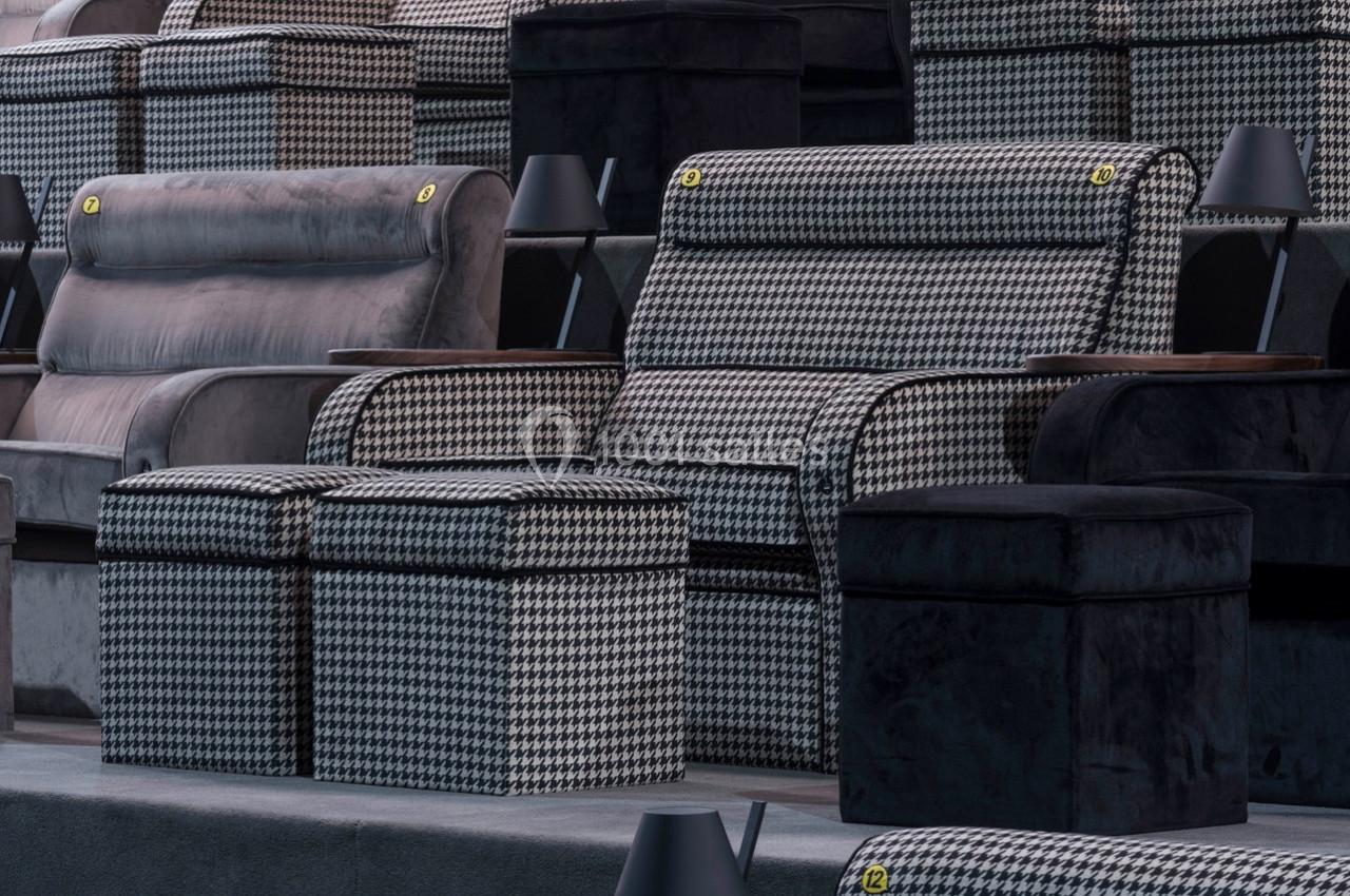 Sièges de cinéma en tissu à motif pied-de-poule avec repose-pieds assortis et accoudoirs en bois.
