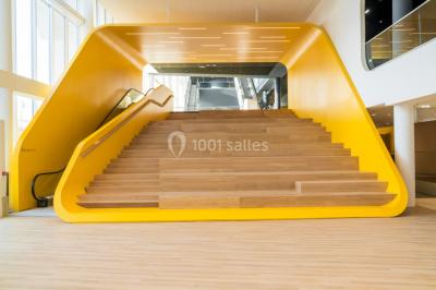 Terrasse extérieure avec mobilier de jardin, vue sur des bâtiments modernes et ciel dégagé en arrière-plan.