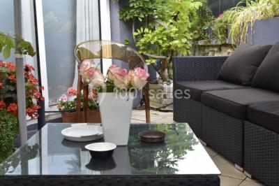 Voiture blanche décorée de fleurs garée devant une maison moderne avec jardin et clôture en métal.