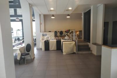 Tables dressées avec des ustensiles de cuisine, planches vertes et ingrédients, dans une salle lumineuse.