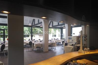 Tables dressées avec des ustensiles de cuisine, planches vertes et ingrédients, dans une salle lumineuse.