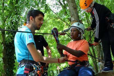 Tables dressées avec des ustensiles de cuisine, planches vertes et ingrédients, dans une salle lumineuse.
