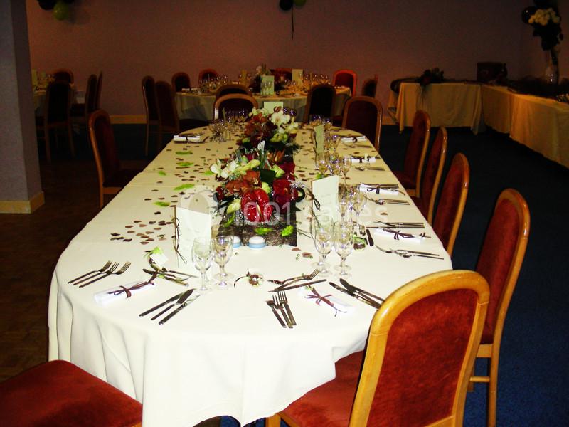 Table dressée pour un repas festif, ornée de fleurs, nappes blanches et couverts disposés avec soin.