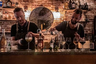 Miniature Location salle Mérindol (Vaucluse) - La Cave à Aimé #4 Bouteilles de spiritueux variés et verres servis sur un tonneau dans un cadre chaleureux de bar ou cave.