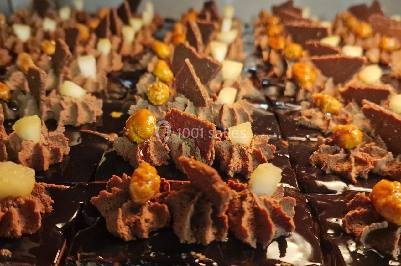 Dessert au chocolat décoré de morceaux de poire, de caramel croquant et de copeaux de chocolat.