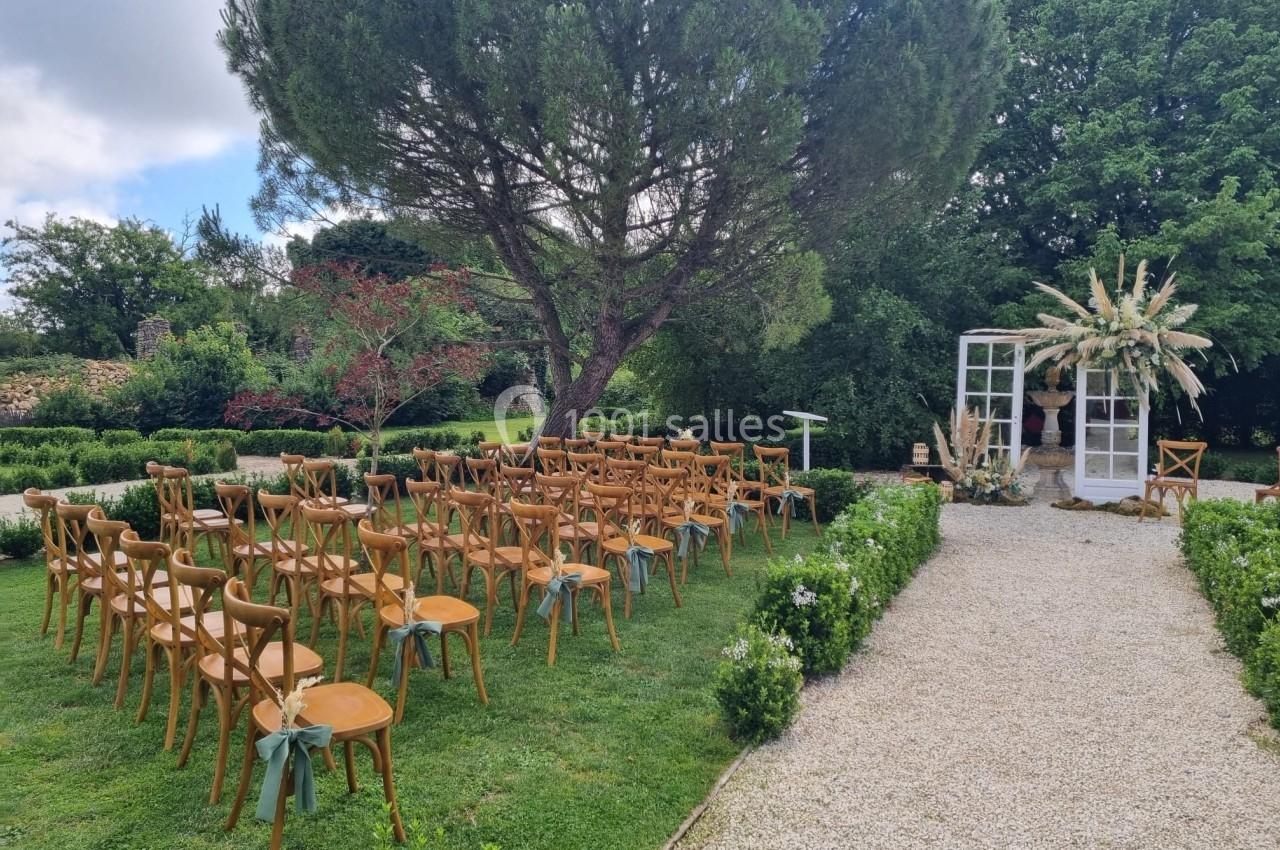 Chaises en bois disposées en rangées sur une pelouse pour une cérémonie en extérieur, entourées de verdure et d'arbres.