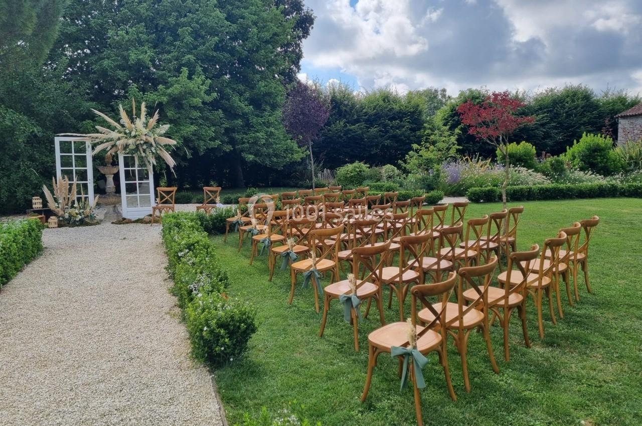 Chaises en bois disposées en rangées sur une pelouse, face à une arche décorée pour une cérémonie en plein air.