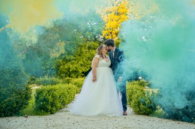 Un homme debout, bras ouverts, s'exprime devant un mur en pierre, avec une chaise en bois à côté de lui.