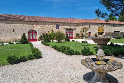 Un homme debout, bras ouverts, s'exprime devant un mur en pierre, une chaise vide à ses côtés.