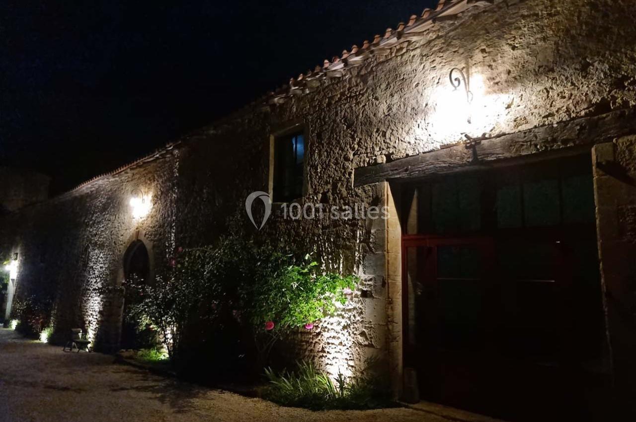 Façade en pierre d'un bâtiment ancien éclairé par des lumières extérieures la nuit.