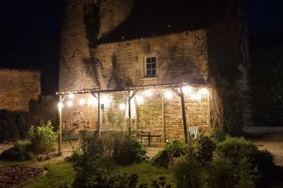 Un homme debout, bras ouverts, s'exprime devant un mur en pierre, une chaise vide à ses côtés.