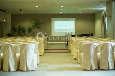 Bâtiment en pierre de style méditerranéen entouré d'arbres, avec une terrasse et une pelouse au premier plan.