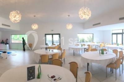 Bâtiment en pierre de style méditerranéen entouré d'arbres, avec une terrasse et une pelouse au premier plan.