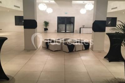 Bâtiment en pierre de style méditerranéen entouré d'arbres, avec une terrasse et une pelouse au premier plan.