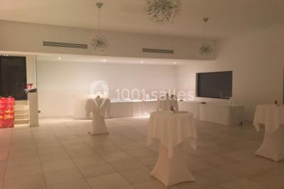 Bâtiment en pierre de style méditerranéen entouré d'arbres, avec une terrasse et une pelouse au premier plan.