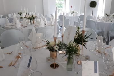 Salle de réception décorée avec des tables rondes recouvertes de nappes rouges, ornées de compositions florales.