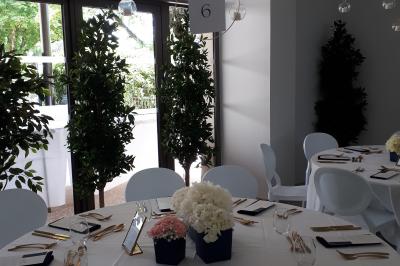 Salle de réception décorée avec des tables rondes recouvertes de nappes rouges, ornées de compositions florales.