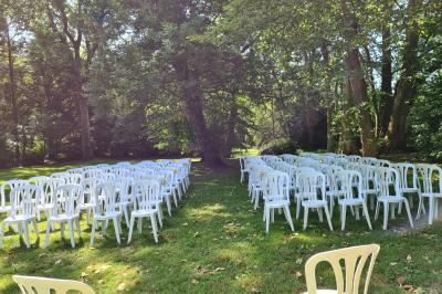 Salle de réception décorée avec des tables rondes recouvertes de nappes rouges, ornées de compositions florales.