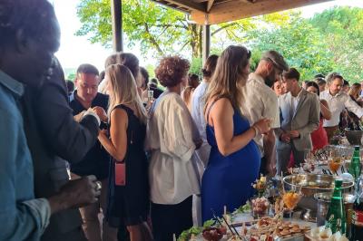Salle de réception décorée avec des tables rondes recouvertes de nappes rouges, ornées de compositions florales.