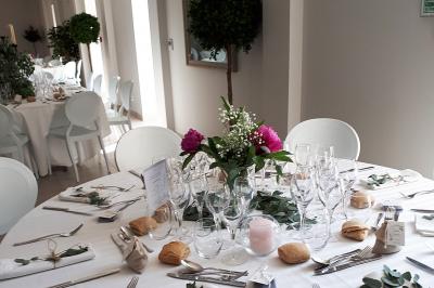Salle de réception décorée avec des tables rondes recouvertes de nappes rouges, ornées de compositions florales.