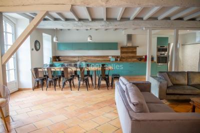 Salle de réception décorée avec des tables rondes recouvertes de nappes rouges, ornées de compositions florales.