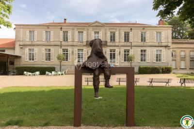 Salle de réception décorée avec des tables rondes recouvertes de nappes rouges, ornées de compositions florales.