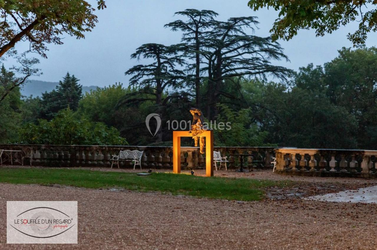 Sculpture lumineuse représentant un chien sur un cadre orange, installée dans un parc au crépuscule.