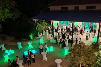 Salle de réception décorée avec des tables rondes recouvertes de nappes rouges, ornées de compositions florales.