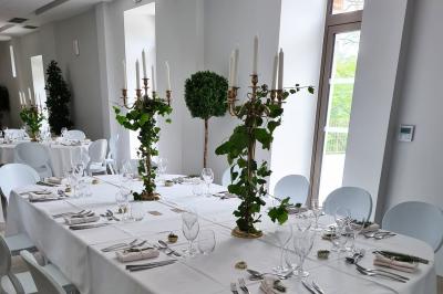 Salle de réception décorée avec des tables rondes recouvertes de nappes rouges, ornées de compositions florales.