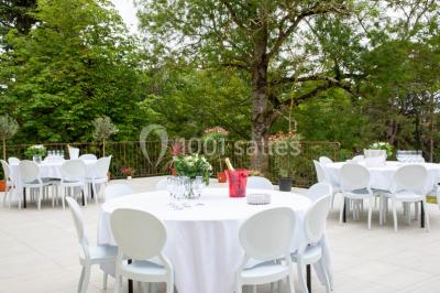 Salle de réception décorée avec des tables rondes recouvertes de nappes rouges, ornées de compositions florales.