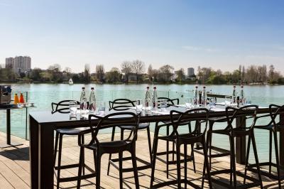Une personne déguste une tartine garnie d'avocat et saumon, entourée de viennoiseries, fruits et boissons sur une table.