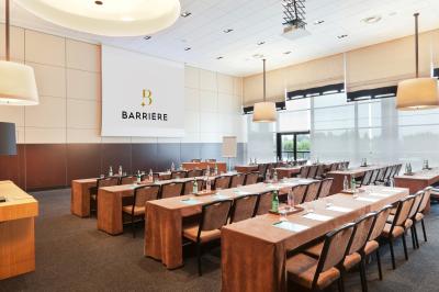 Une personne déguste une tartine garnie d'avocat et saumon, entourée de viennoiseries, fruits et boissons sur une table.