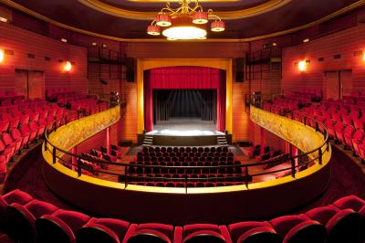 Une personne déguste une tartine garnie d'avocat et saumon, entourée de viennoiseries, fruits et boissons sur une table.