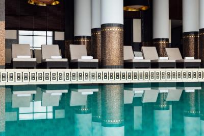 Une personne déguste une tartine garnie d'avocat et saumon, entourée de viennoiseries, fruits et boissons sur une table.