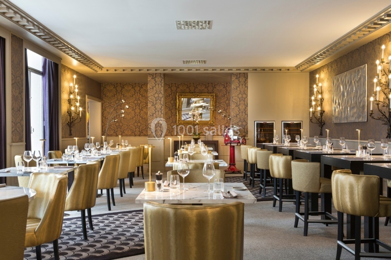 Salle de restaurant élégante avec tables dressées, chaises dorées et décoration murale raffinée.