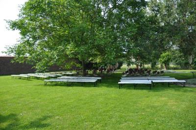 Salle de réception en briques avec tables rondes dressées, nappes blanches et décoration de mariage.